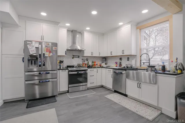 a kitchen with kitchen island white cabinets and stainless steel appliances