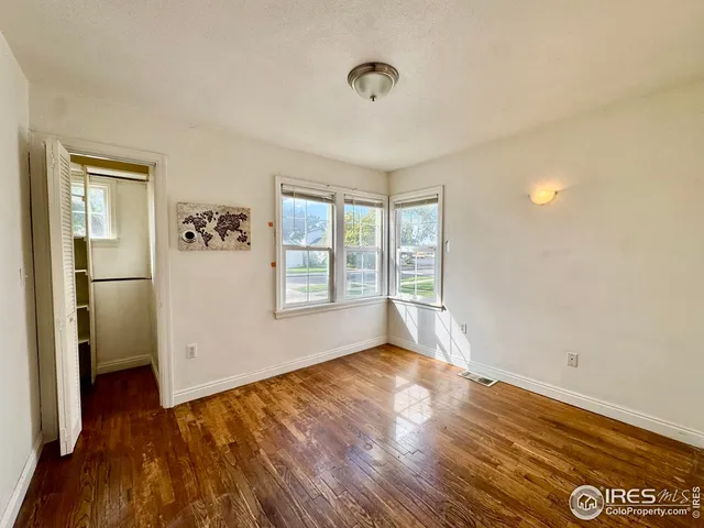 a view of empty room with wooden floor and fan
