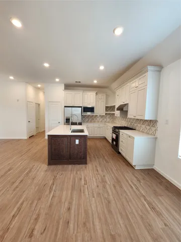 a large kitchen with stainless steel appliances granite countertop a large counter top a sink and a dishwasher