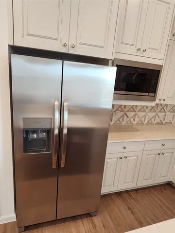 a kitchen with granite countertop white cabinets and stainless steel appliances