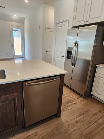 a room with wooden floor and stainless steel appliances