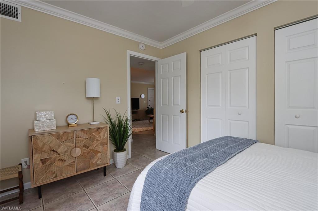 940 3rd Street South, Unit 101 Naples, FL 34102 - Photo 17 of 20 Bedroom with crown molding, tile patterned flooring, two closets, and ceiling fan