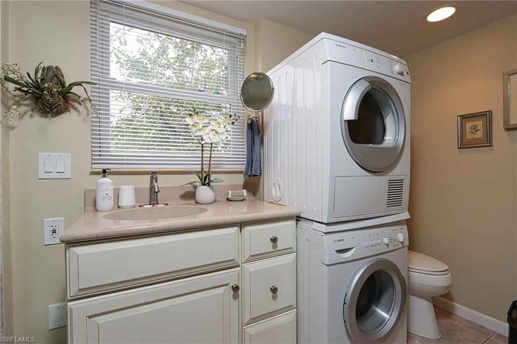 940 3rd Street South, Unit 101 Naples, FL 34102 - Photo 18 of 20 Laundry area with stacked washer and clothes dryer, light tile patterned floors, and recessed lighting