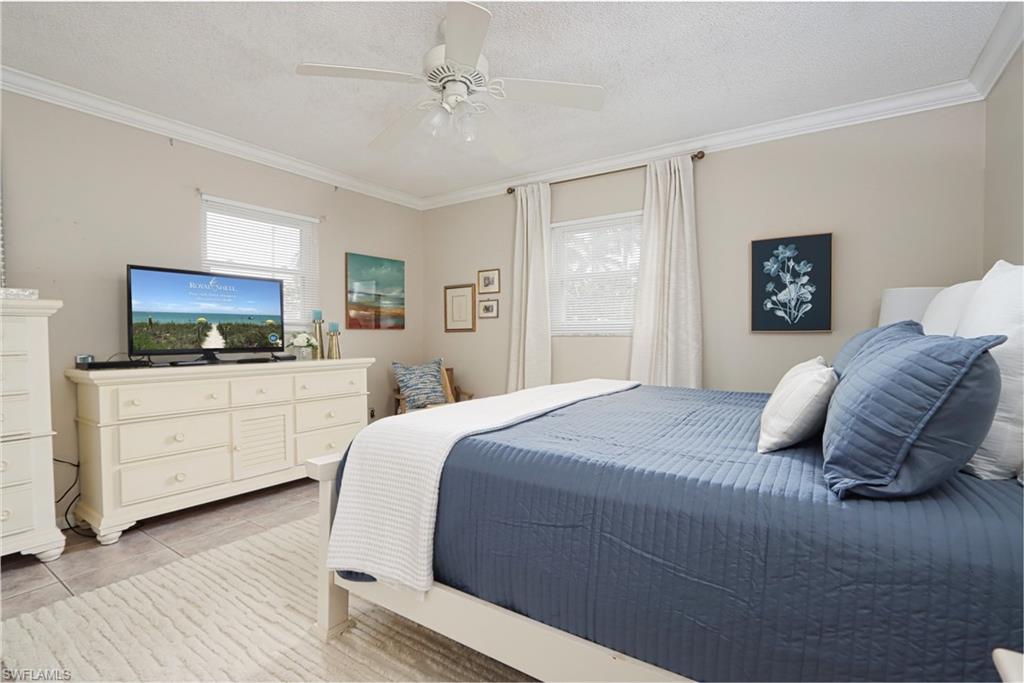 940 3rd Street South, Unit 101 Naples, FL 34102 - Photo 5 of 20 Bedroom featuring crown molding, a textured ceiling, multiple windows, a ceiling fan, and light tile patterned floors