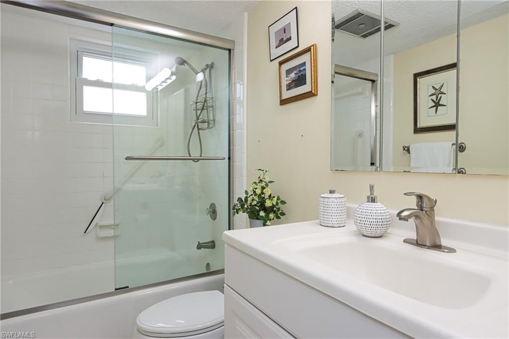 940 3rd Street South, Unit 101 Naples, FL 34102 - Photo 6 of 20 Full bath featuring combined bath / shower with glass door, vanity, and a textured ceiling