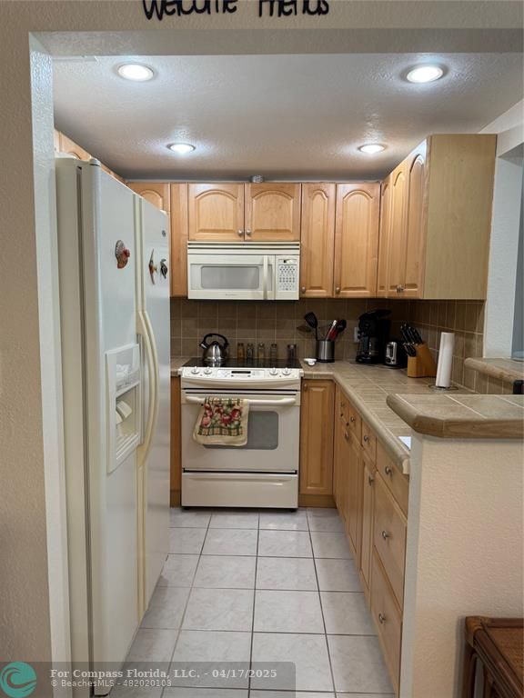 42 Tilford C, Unit 42 Deerfield Beach, FL 33442 - Photo 42 of 50 a kitchen with a stove a sink and a refrigerator