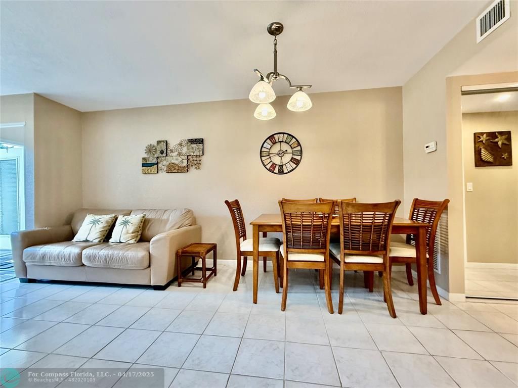 42 Tilford C, Unit 42 Deerfield Beach, FL 33442 - Photo 46 of 50 a living room with couches a dining table and a clock on the wall