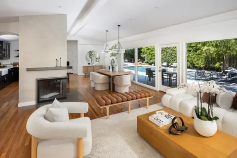 a living room with furniture a fireplace and a floor to ceiling window