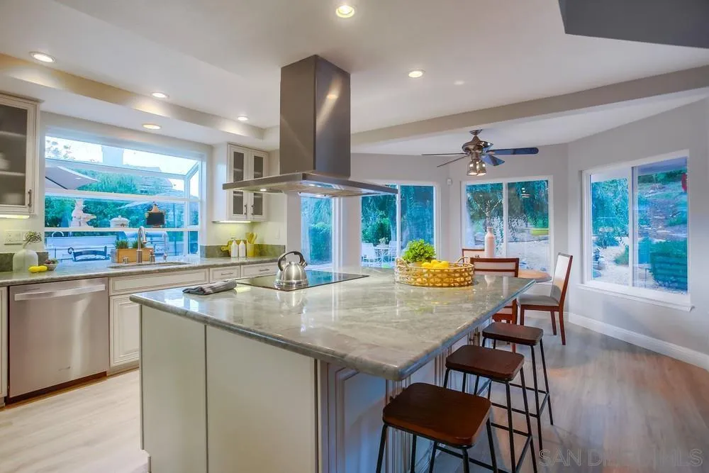a kitchen with stainless steel appliances granite countertop a table chairs and a wooden floor