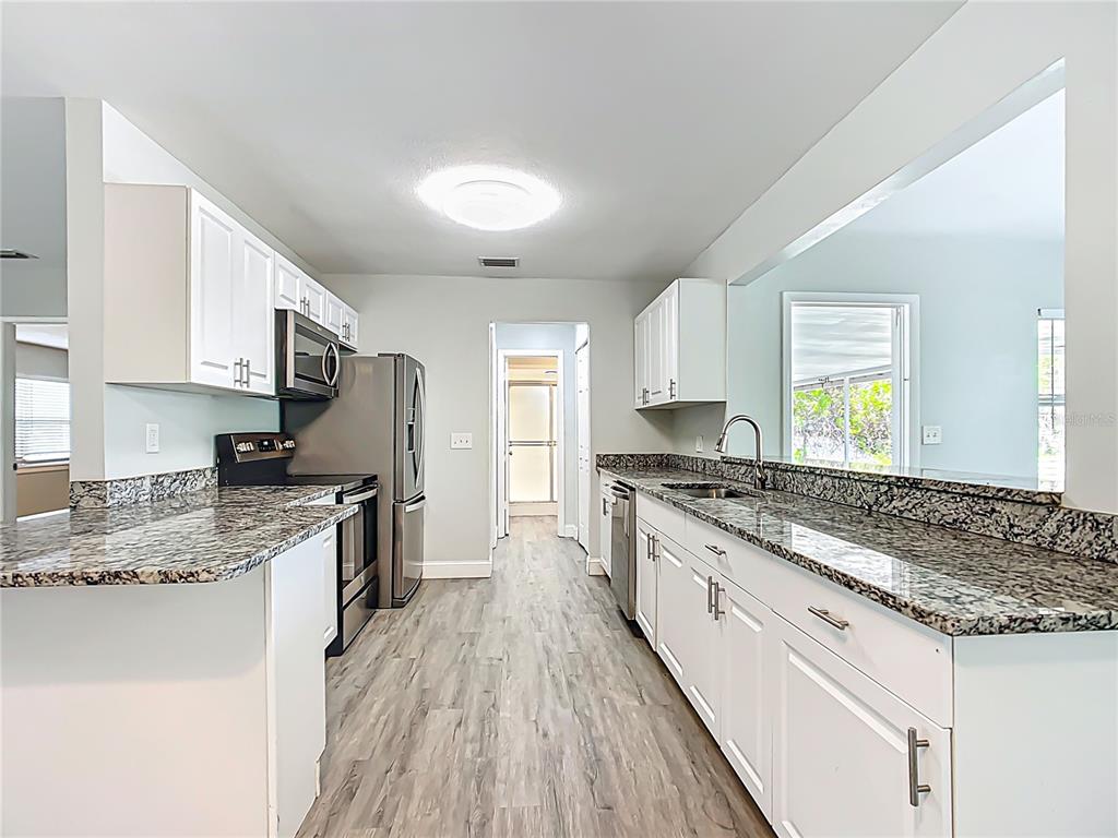 1406 Eden Drive Inverness, FL 34450 - Photo 9 of 41 a kitchen with granite countertop stainless steel appliances a stove top oven a sink a counter space and cabinets