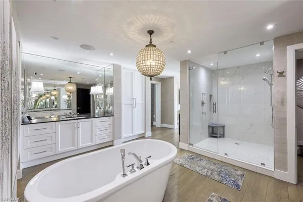 a bathroom with a tub a sink and a large mirror
