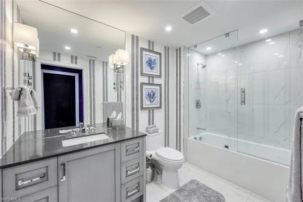 a bathroom with a granite countertop sink a toilet a mirror and shower