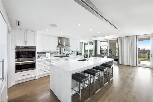 a large white kitchen with stainless steel appliances and a stove