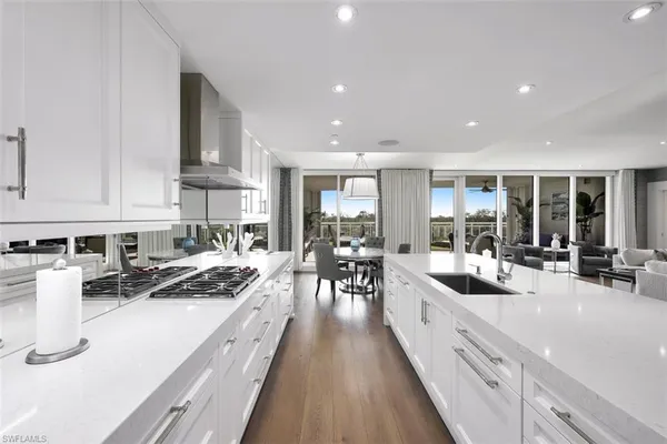 a kitchen with stainless steel appliances a stove a sink a cabinets and chairs