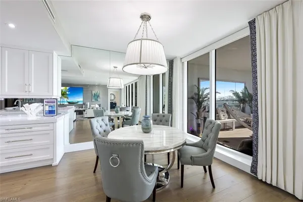 a dining room with wooden floor a chandelier a glass table and chairs