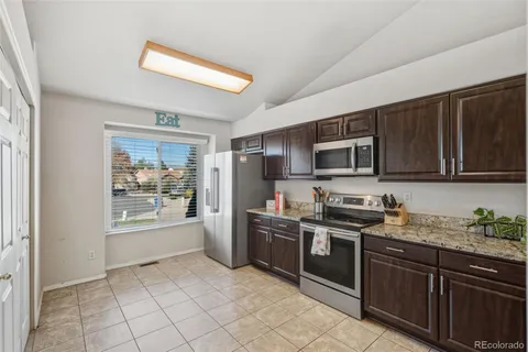 a kitchen with stainless steel appliances granite countertop a stove top oven a sink dishwasher a refrigerator and cabinets with wooden floor