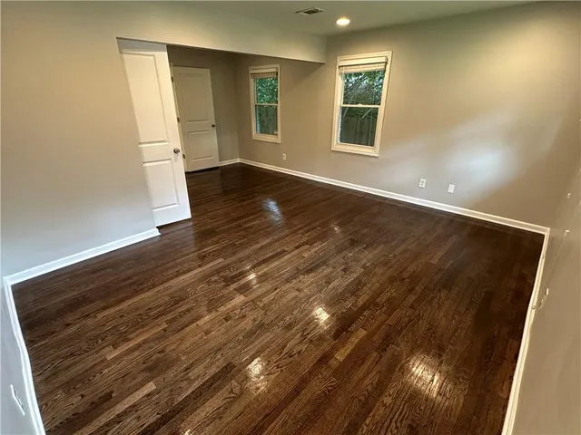 an empty room with wooden floor and windows