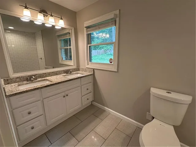 a bathroom with a granite countertop toilet sink and mirror