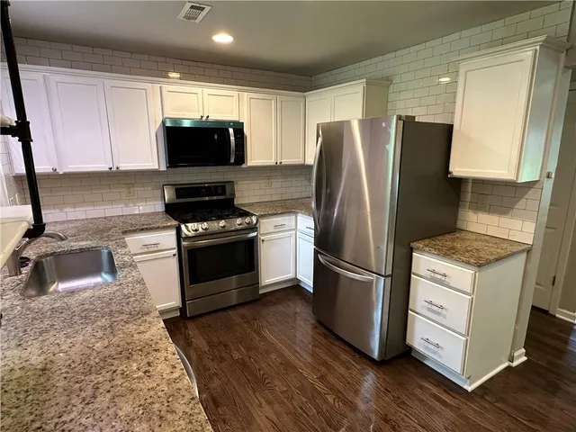 a kitchen with granite countertop a refrigerator stove and sink