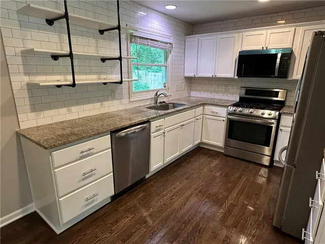 a kitchen with stainless steel appliances white cabinets a sink and a stove