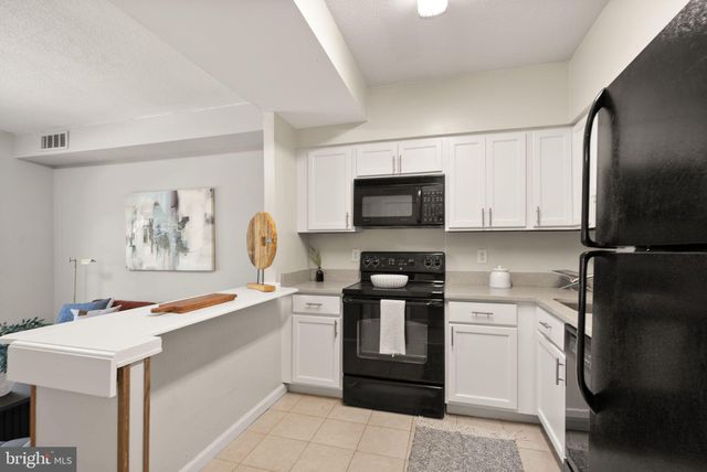 a view of kitchen with stainless steel appliances granite countertop a sink stove top oven and cabinets
