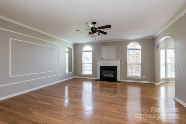 an empty room with wooden floor fireplace and windows