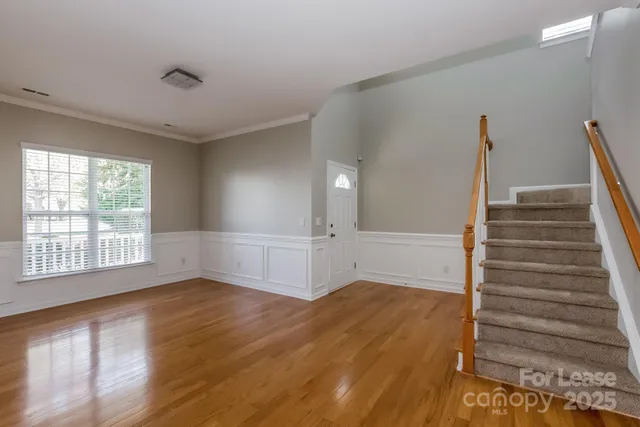 a view of an empty room with wooden floor and window