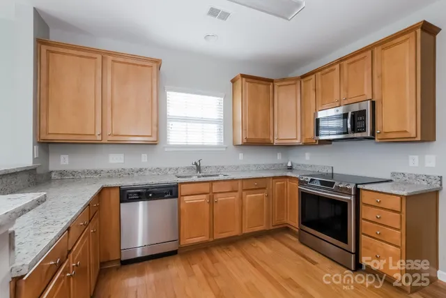 a kitchen with stainless steel appliances granite countertop wooden cabinets and a stove top oven
