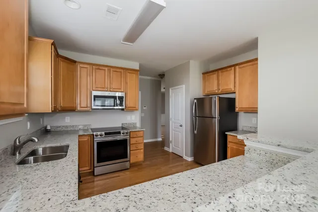 a kitchen with stainless steel appliances granite countertop a refrigerator stove and sink