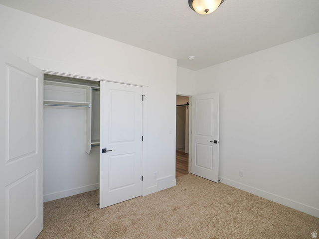 3938 North Wood Road Eagle Mountain, UT 84005 - Photo 25 of 55 Unfurnished bedroom featuring a closet and light colored carpet