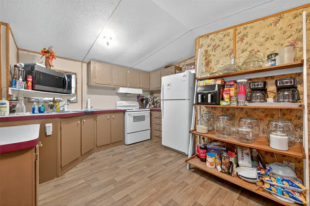 a kitchen with stainless steel appliances a refrigerator and a wooden floor