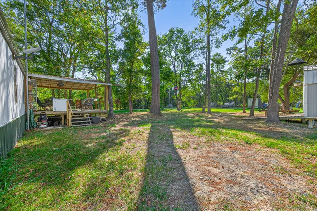 a view of backyard with table and chairs and large trees