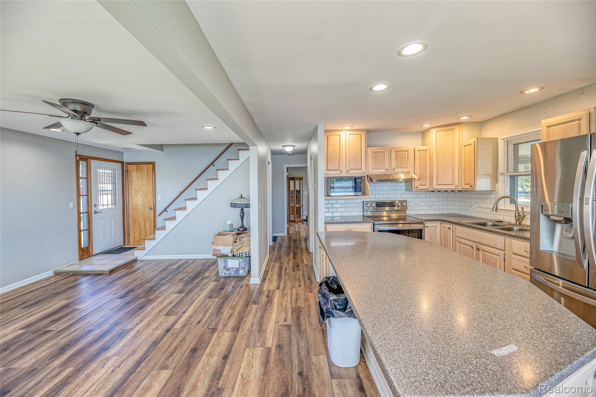 2855 Farmers Creek Road Metamora, MI 48455 - Photo 13 of 51 Open-concept kitchen and living area featuring wood-finish flooring, a kitchen island with a solid surface countertop, stainless steel appliances, and shaker-style cabinetry