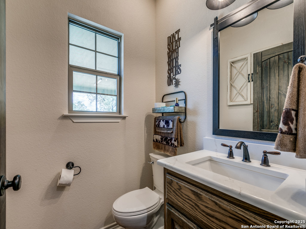 6451 Bluntzer Road Jourdanton, TX 78026 - Photo 20 of 51 a bathroom with a granite countertop sink toilet a mirror and shower