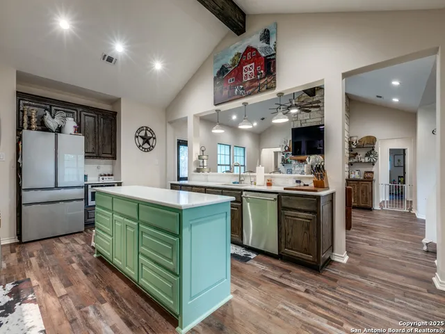 a kitchen with stainless steel appliances kitchen island granite countertop a refrigerator and a stove top oven
