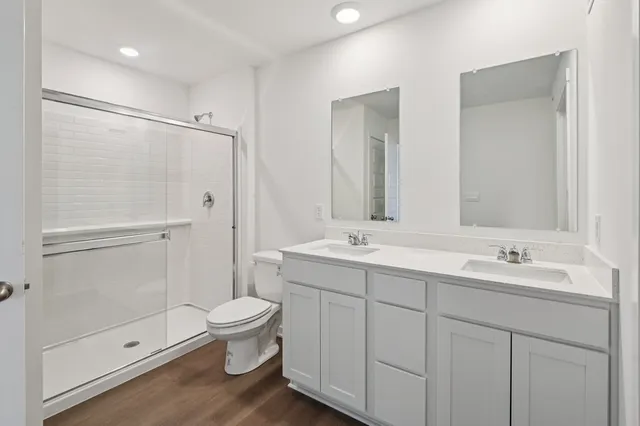 a bathroom with a double vanity sink toilet mirror and shower