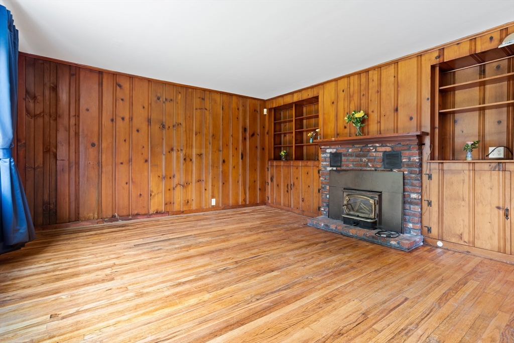 69 East Road Westminster, MA 01473 - Photo 3 of 17 an empty room with wooden floor fireplace and windows