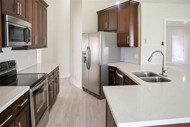 a kitchen with stainless steel appliances a refrigerator a sink a stove and microwave