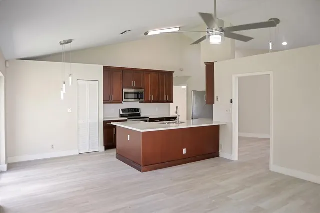 a kitchen with stainless steel appliances granite countertop a stove a refrigerator a sink a refrigerator and white cabinets with wooden floor