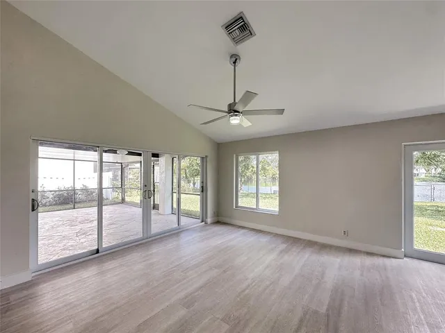 a view of an empty room with a window and wooden floor