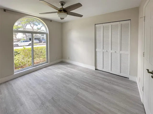 an empty room with wooden floor fan and a window