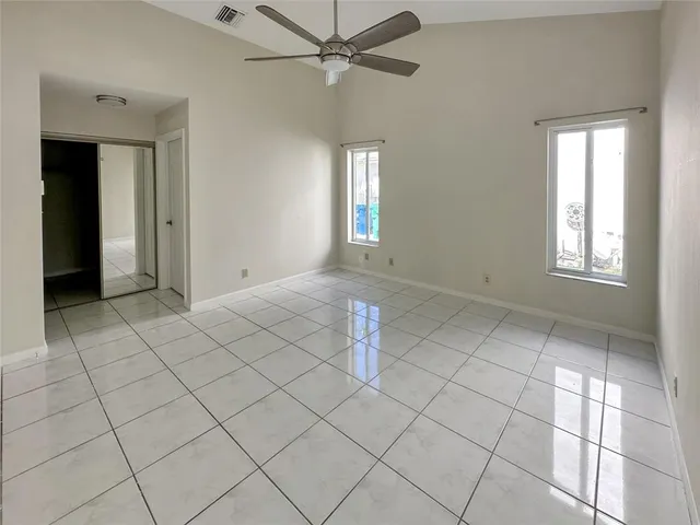 an empty room with windows and fan