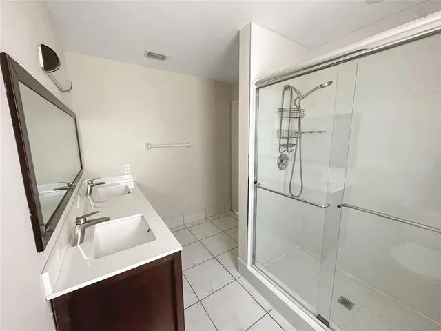 a bathroom with a sink a glass door shower and mirror