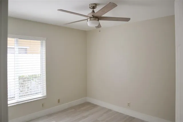 an empty room with a window and a fan