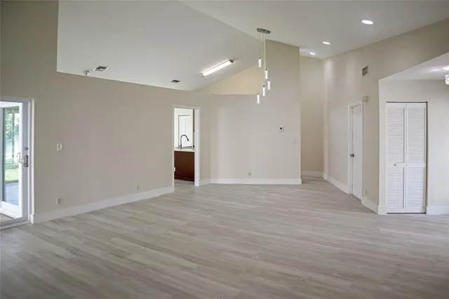 a view of an empty room with wooden floor and windows