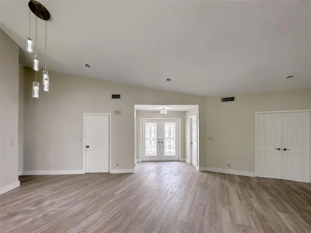 a view of an empty room with window and wooden floor