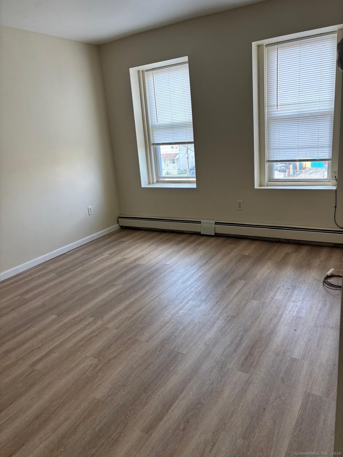 1057 East Main Street Bridgeport, CT 06608 - Photo 5 of 9 an empty room with wooden floor and windows