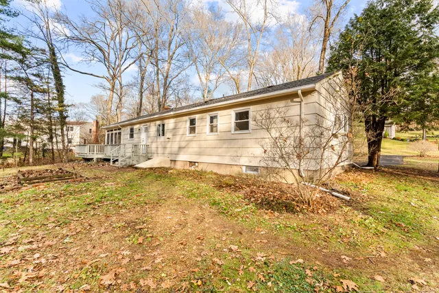 a backyard of a house with large trees and outdoor seating