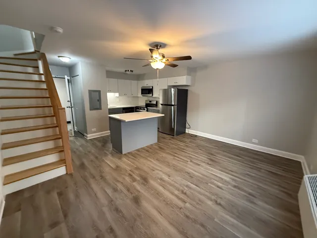 a view of a kitchen with wooden floor and a ceiling fan