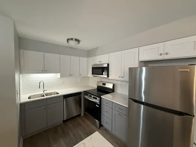 a kitchen with a sink a refrigerator and white cabinets
